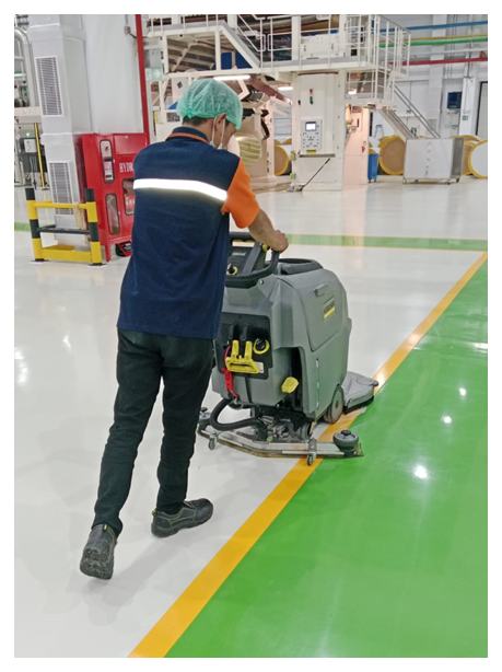 Ride-on scrubber machine operation in factory